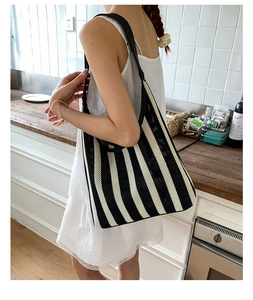 Detail of woven black and white vertical stripe knit hobo bag with hollow mesh texture