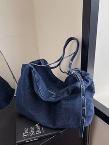 Versatile dark blue denim tote bag with adjustable metal eyelet strap and hobo style design