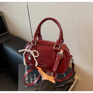 Detail of red oil-wax leather Boston bag with pearl bow and silver heart pendant