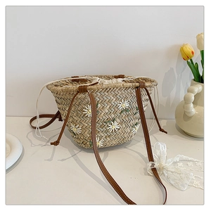 Close-up of handmade straw bucket bag with white daisy embroidery and drawstring lining