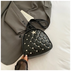 Macro shot of quilted black faux leather with a sparkling rhinestone star detail on the bag