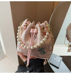 Détail du sac seau en jacquard rose avec broderie chinoise et poignée en perles