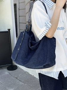 Large blue denim tote bag with silver metal eyelets and adjustable strap for women