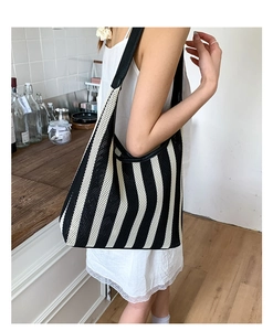 Detail of a black and white striped mesh tote bag with black leather shoulder straps