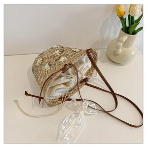 Detailed macro view of woven straw bucket bag featuring embroidered daisy flower patterns