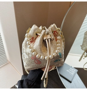 Détail d'un sac seau brodé chinois avec poignée en perles et texture en soie élégante