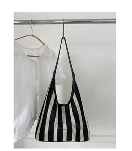 Close-up of black and white striped woven tote bag with slim leather straps on hanger