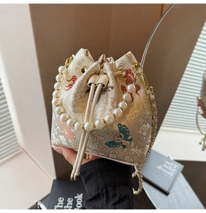 Détail du sac seau brodé style chinois avec anse en perles et chaîne dorée élégante