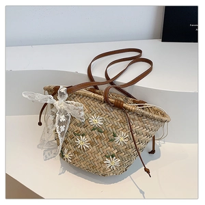 Detail of straw bucket bag with white daisy embroidery and a delicate lace bow