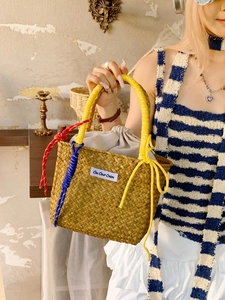 Handmade woven straw bucket bag with yellow rope handles for summer beach vacations