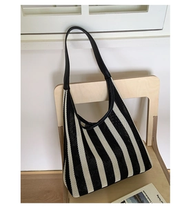Detailed texture of black and white vertical striped woven tote bag with leather strap