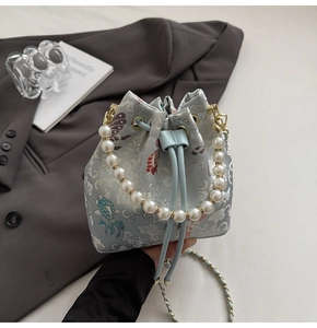 Vue détaillée d'un sac seau brodé bleu clair avec poignée en perles et chaîne