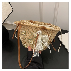 Detail of straw bucket bag with daisy embroidery, lace bow, and drawstring closure