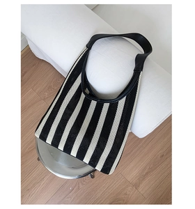Detailed view of the black and white vertical striped knit tote bag with leather strap