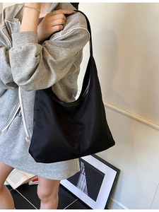 Large black nylon hobo bag for women worn by a model in a minimalist style