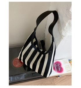 Detail of black and white striped knit underarm bag with breathable mesh texture