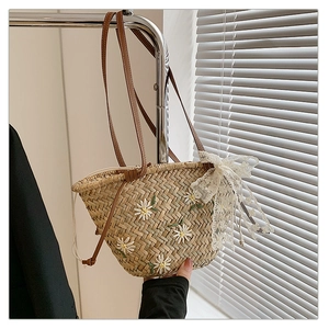 Detailed macro view of straw bucket bag with daisy embroidery and lace bow accent