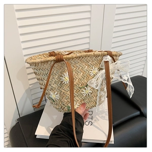 Detail of handmade straw bucket bag with white daisy embroidery and lace bow decoration