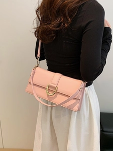 Sac à bandoulière en cuir rose avec boucle dorée en fer à cheval porté par un mannequin