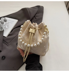 Détails de broderie papillon et poignée en perles sur un sac seau crème à chaîne