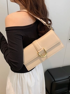 Sac sous le bras chic en cuir crème avec boucle fer à cheval dorée sur un mannequin