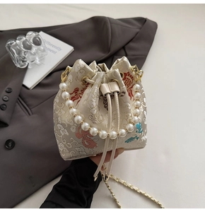 Détails de broderie chinoise, poignée en perles et texture soyeuse du sac seau