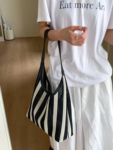 Modern black and white striped mesh tote bag with black leather straps shown on a model