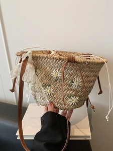 Handwoven straw bucket bag with floral embroidery and lace trim for summer beach vacations