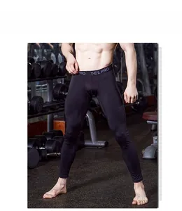 Detail of men's black pro compression pants with wide elastic waistband in a gym setting