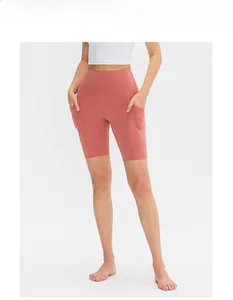 Dettaglio dei pantaloncini da yoga corallo a vita alta con tasche laterali e cuciture