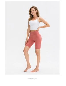 Dettaglio dei pantaloncini da yoga corallo a vita alta con tasca laterale e top bianco
