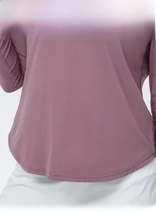 Detail of the curved hem design on a dusty pink long-sleeved athletic yoga top for women