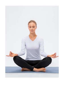 Detail of white V-neck long sleeve yoga top and black leggings on a blue mat