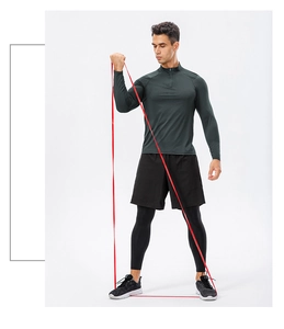 Red elastic resistance band used by man wearing half-zip fitness training sweatshirt