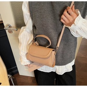 Detail of a light brown PU leather crossbody bag worn by a model in a cozy indoor setting