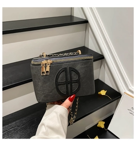 Detailed view of dark grey textured mini box bag with gold HB emblem and chain strap
