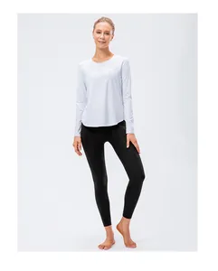 Women's long sleeve white yoga top with curved hem and black leggings set for fitness