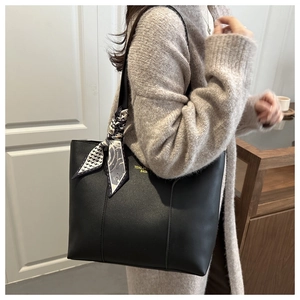 Detail of black tote bag featuring matte leather texture and decorative printed silk scarf