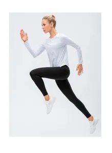 Dynamic professional shot of women's white long sleeve yoga top and black fitness leggings