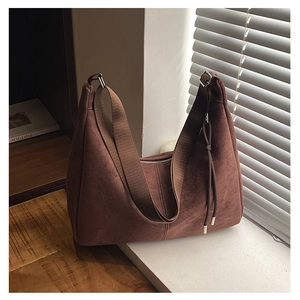 Detail of soft brown suede hobo bag featuring zipper closure and stylish metal pendant strap