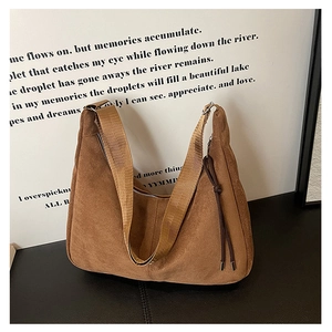 Detail of a brown suede hobo bag with wide shoulder strap and knotted tassel accent