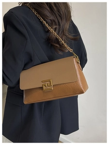 Close-up of brown patchwork crossbody bag with gold metal chain and geometric buckle