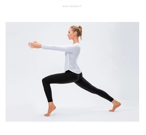Detail view of white long-sleeve yoga top with curved hem and black high-waist leggings
