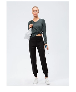 Détail du haut de yoga ample à col en V avec un nœud avant en tissu vert foncé