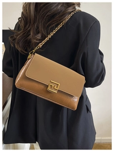 Detail of light brown crossbody bag with gold chain strap and geometric metal lock