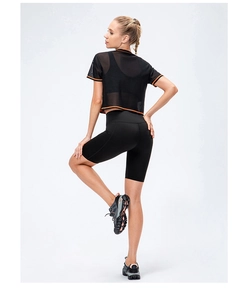 Detail of loose black mesh short-sleeve yoga top with orange trim and athletic shorts