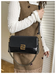 Detail of black patchwork shoulder bag with gold metal buckle and dual strap style