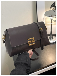 Close-up of deep brown crossbody bag featuring golden geometric interlocking clasp detail