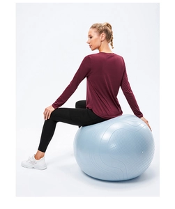 Détail du haut de yoga bordeaux à manches longues porté par un mannequin sur un ballon