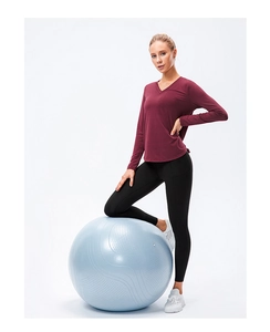 Vue détaillée du haut de yoga bordeaux et legging noir sur un ballon de fitness